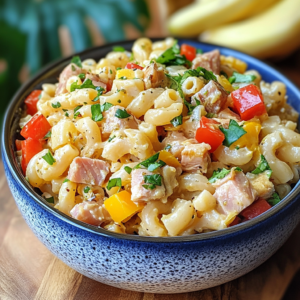 Bowl of creamy Hawaiian mac salad with carrots and celery on a tropical background